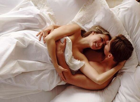 Frau im Bett mit einem Mann, der seinen Schwanz vergrößert